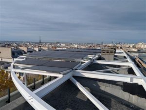 Vue d’une toiture ombrière équipée de panneaux photovoltaïques au sein d’une école primaire située dans le 10ᵉ arrondissement de Paris, avec une vue sur tout Paris.